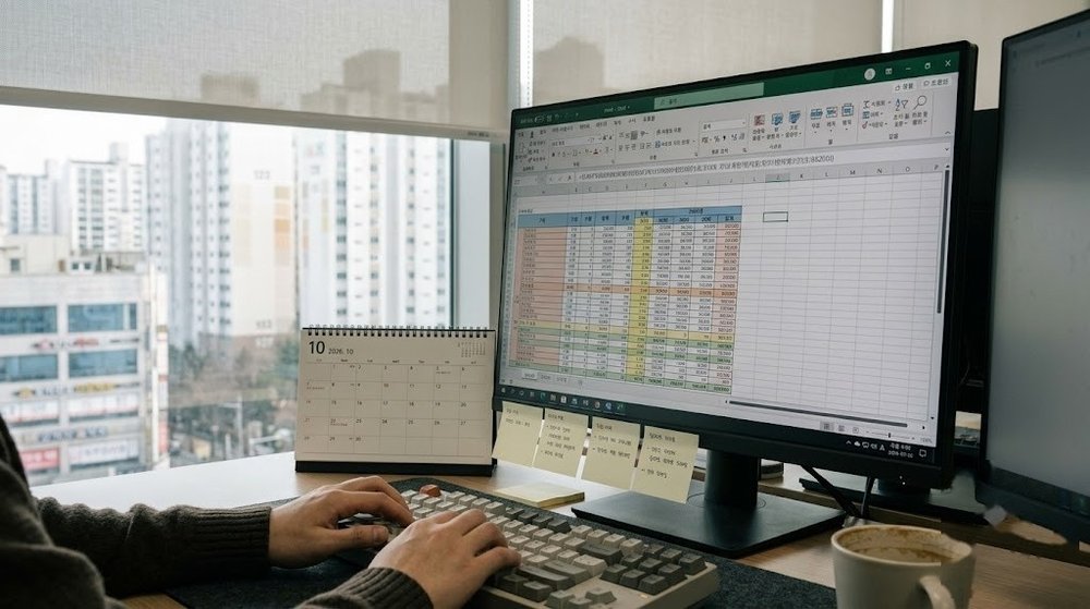 엑셀 스프레드시트 화면과 키보드를 조작하는 책상 환경